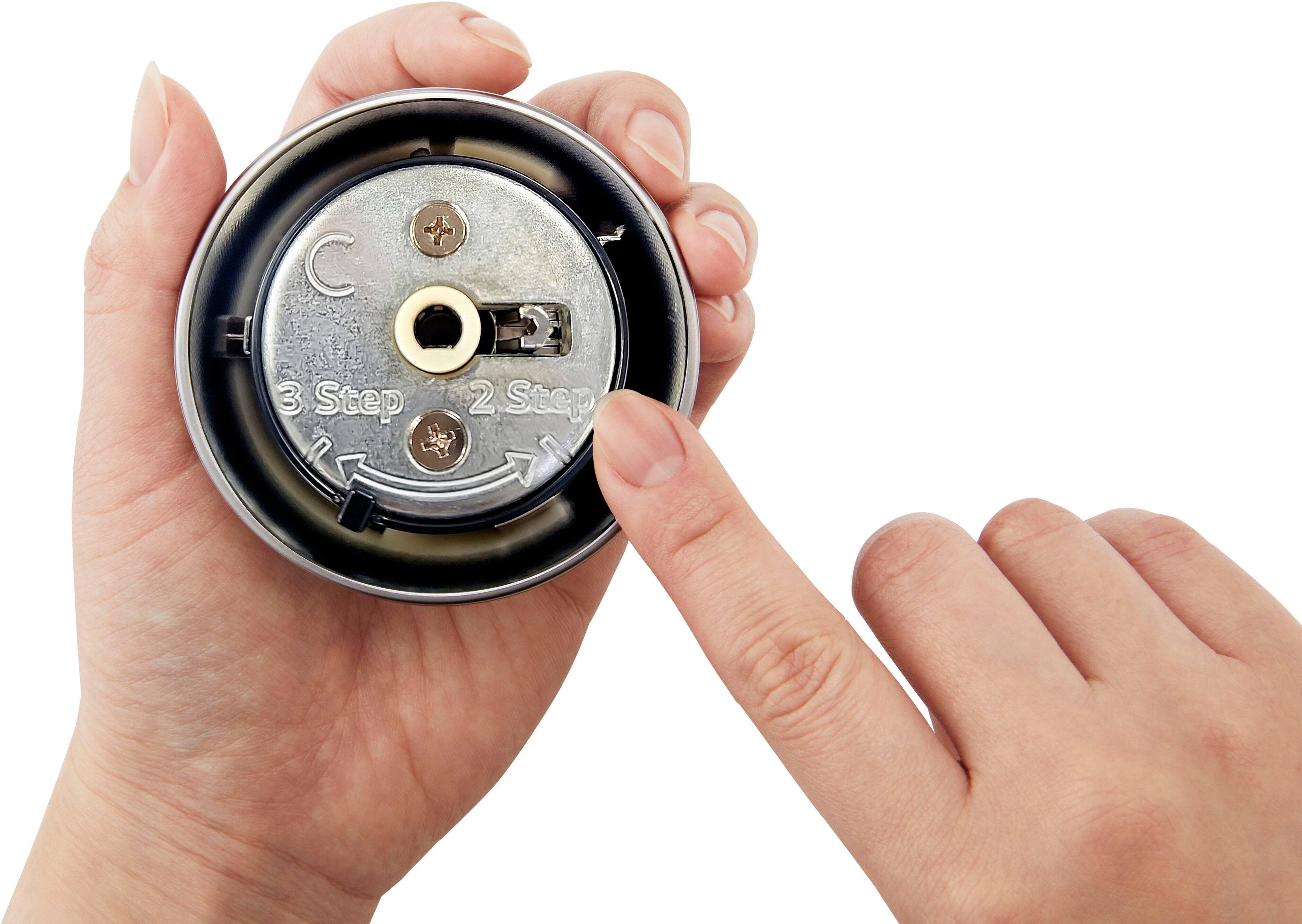 The image shows a person holding a small object, possibly a watch or a piece of machinery, in their hands. The person is carefully examining the object, possibly trying to figure out how to use it or fix it. The hands are positioned in such a way that they are holding the object securely, and the person appears to be focused on the task at hand.