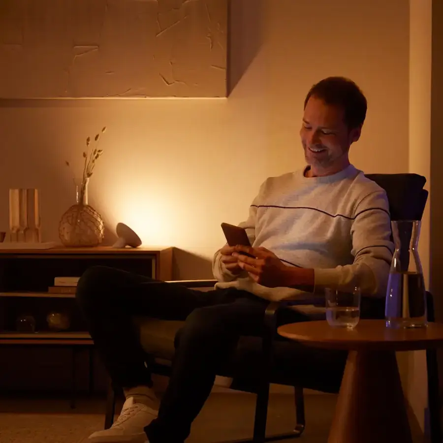 The text on the image is not related to the image content. The image shows a man sitting in a chair, holding a cell phone.