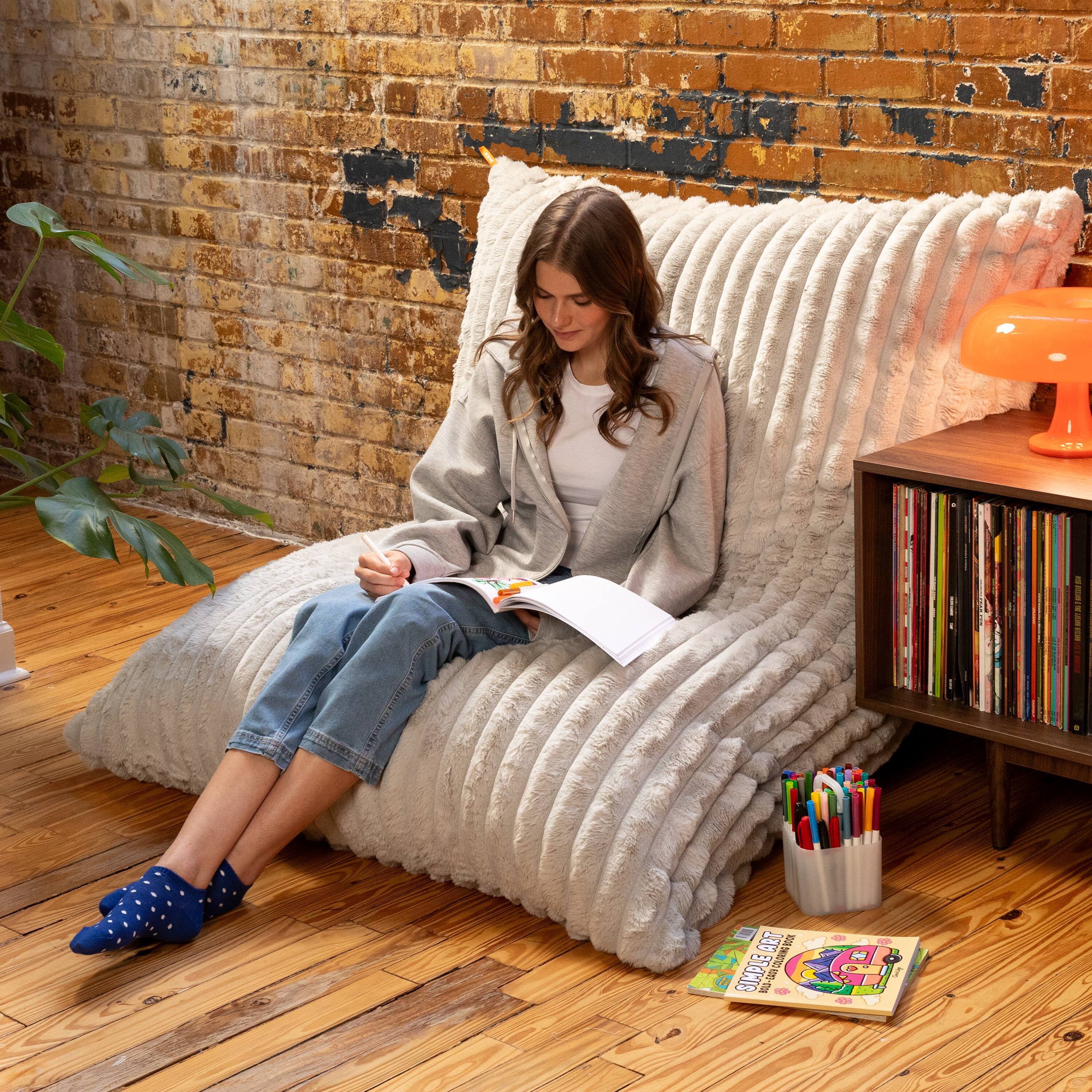 Sure, here is the corrected and grouped text from the image:

**On the book on the floor:**
- "COLORING BOOK"
- "COLORING BOOK"
- "COLORING BOOK"

**On the bookshelf:**
- Various book titles are visible, but they are not fully legible.

**On the notebook:**
- The text is not fully legible.

**On the lamp:**
- No visible text.

**On the wall:**
- No visible text.

**On the person's clothing:**
- No visible text.

**On the pen holder:**
- No visible text.

**On the socks:**
- No visible text.

If you need more specific details or corrections, please let me know!