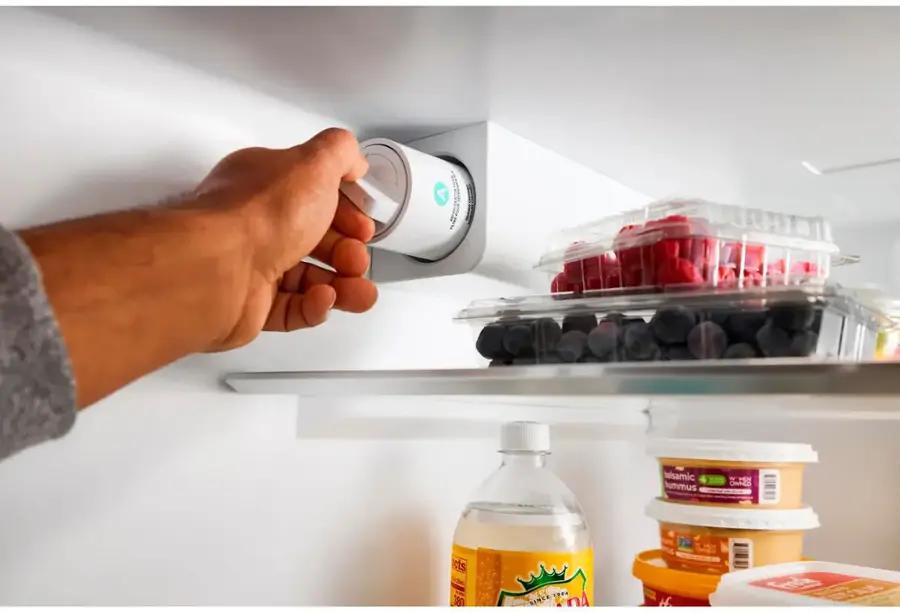 A person is standing in front of an open refrigerator. The refrigerator contains a variety of food items, including strawberries, blueberries, and other fruits. There are also bottles of drinks, such as water and juice, stored in the refrigerator. The person is reaching for a bottle of water, possibly to quench their thirst or prepare a meal. The refrigerator is well-stocked, providing a variety of options for the person to choose from.