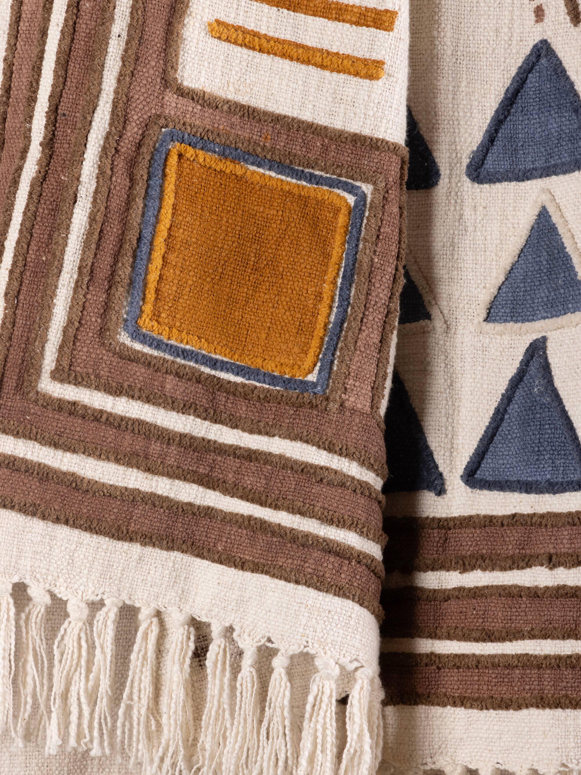 Left. GAURI KOHLI - Aarya Throw Blanket - Shades of beige, brown and blue.