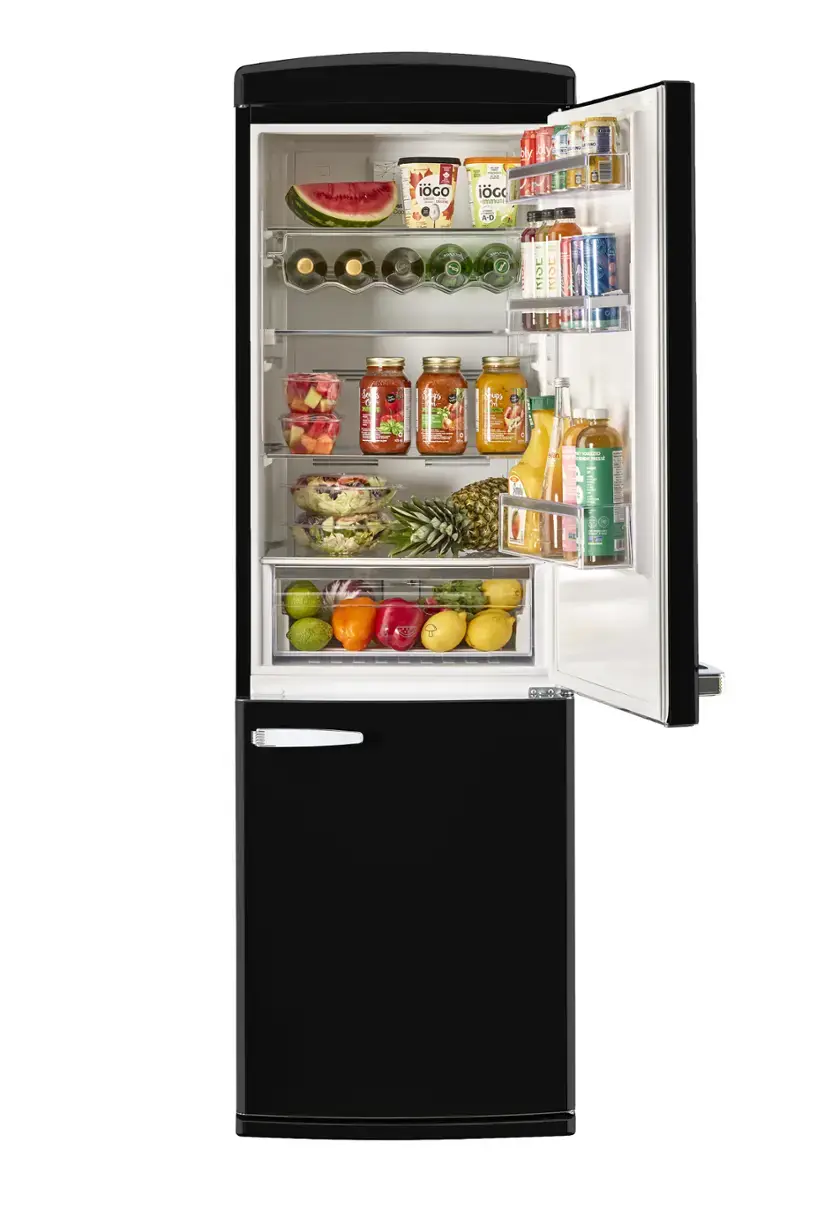The image shows a refrigerator with its door open, revealing a variety of food items inside. There are several bottles of drinks, including juice, and a few apples placed on different shelves. The refrigerator also contains a watermelon, which is placed on the top shelf. The assortment of food and drinks indicates that the refrigerator is well-stocked and ready for use.