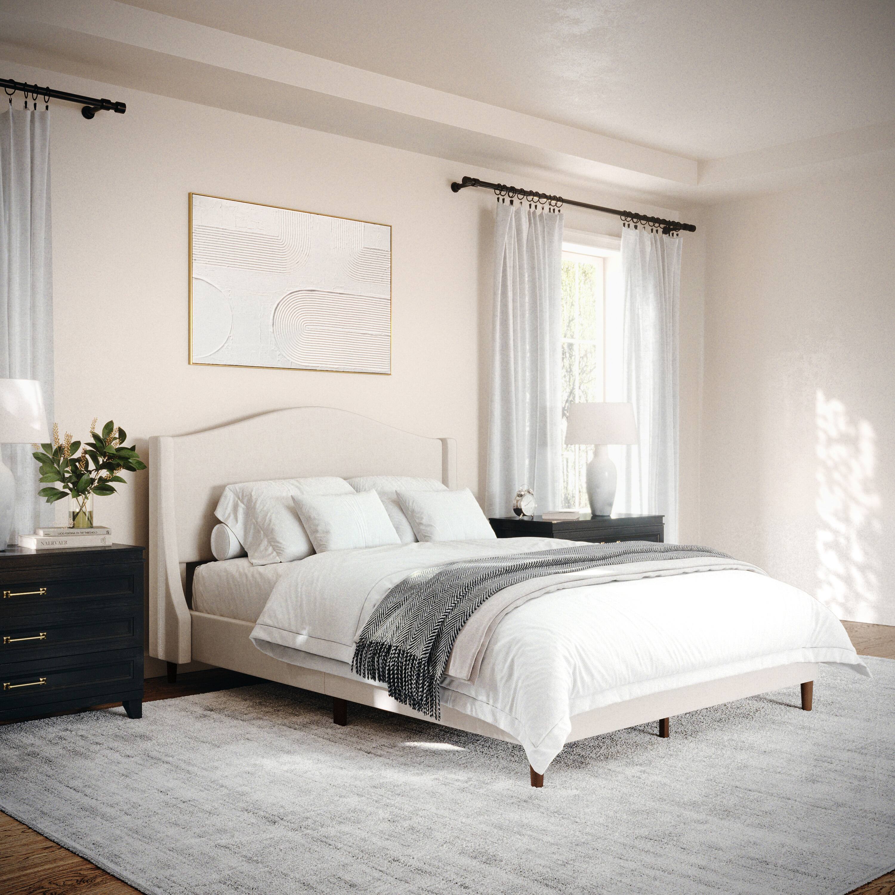 The image shows a large bedroom with a bed that is neatly made with white sheets and a striped comforter. The bed is positioned in front of a window, and there are two lamps on either side of the bed, providing ample lighting. The room also features a dresser and a nightstand, adding to the overall functionality of the space. The bedroom is well-lit, creating a comfortable and inviting atmosphere.