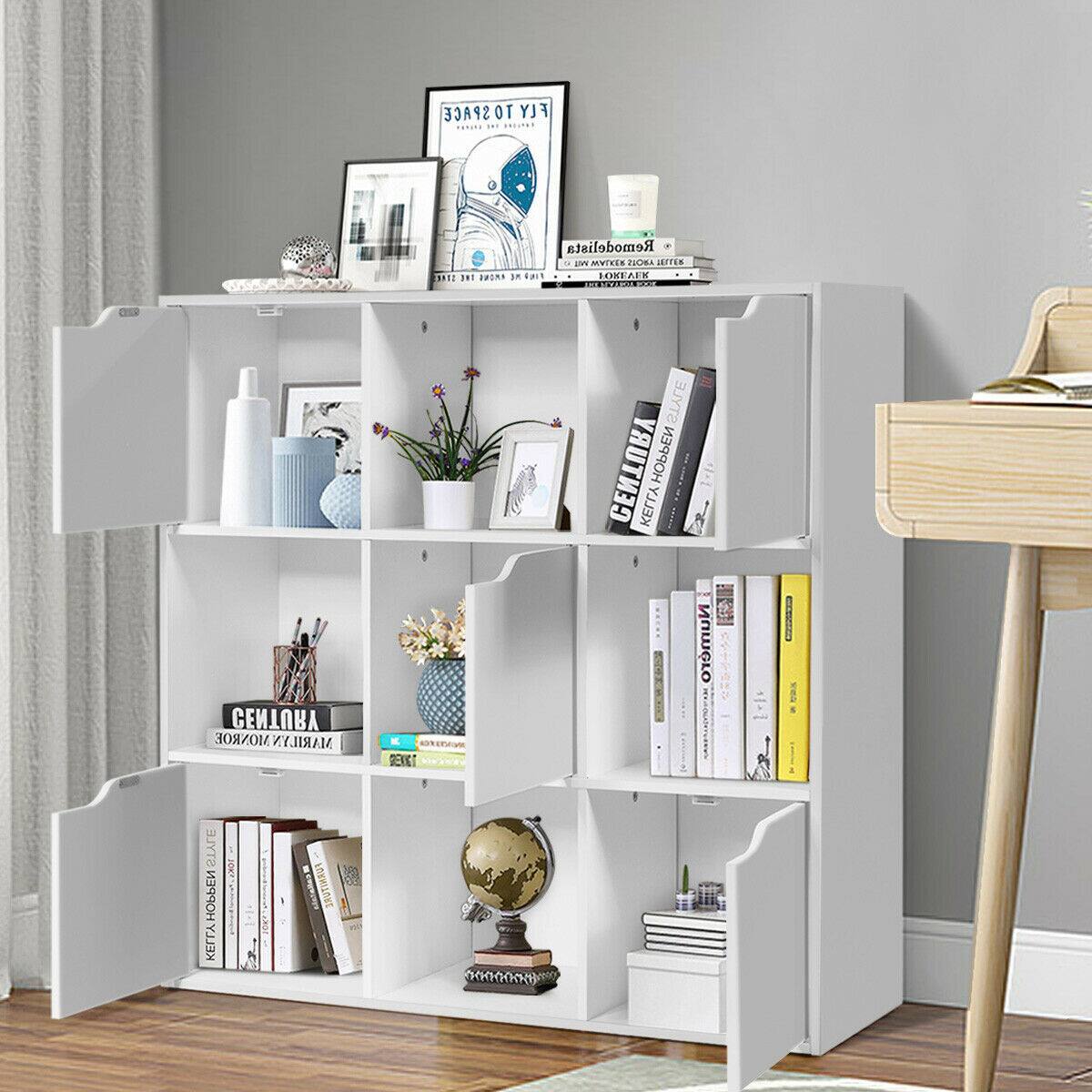 The image features a white bookshelf with various items on it. There are several books of different sizes placed on the shelves, along with a vase and a potted plant. Additionally, there is a clock on the shelf, and a bottle is located nearby. The bookshelf is situated next to a desk, creating a cozy and organized space for reading and working.