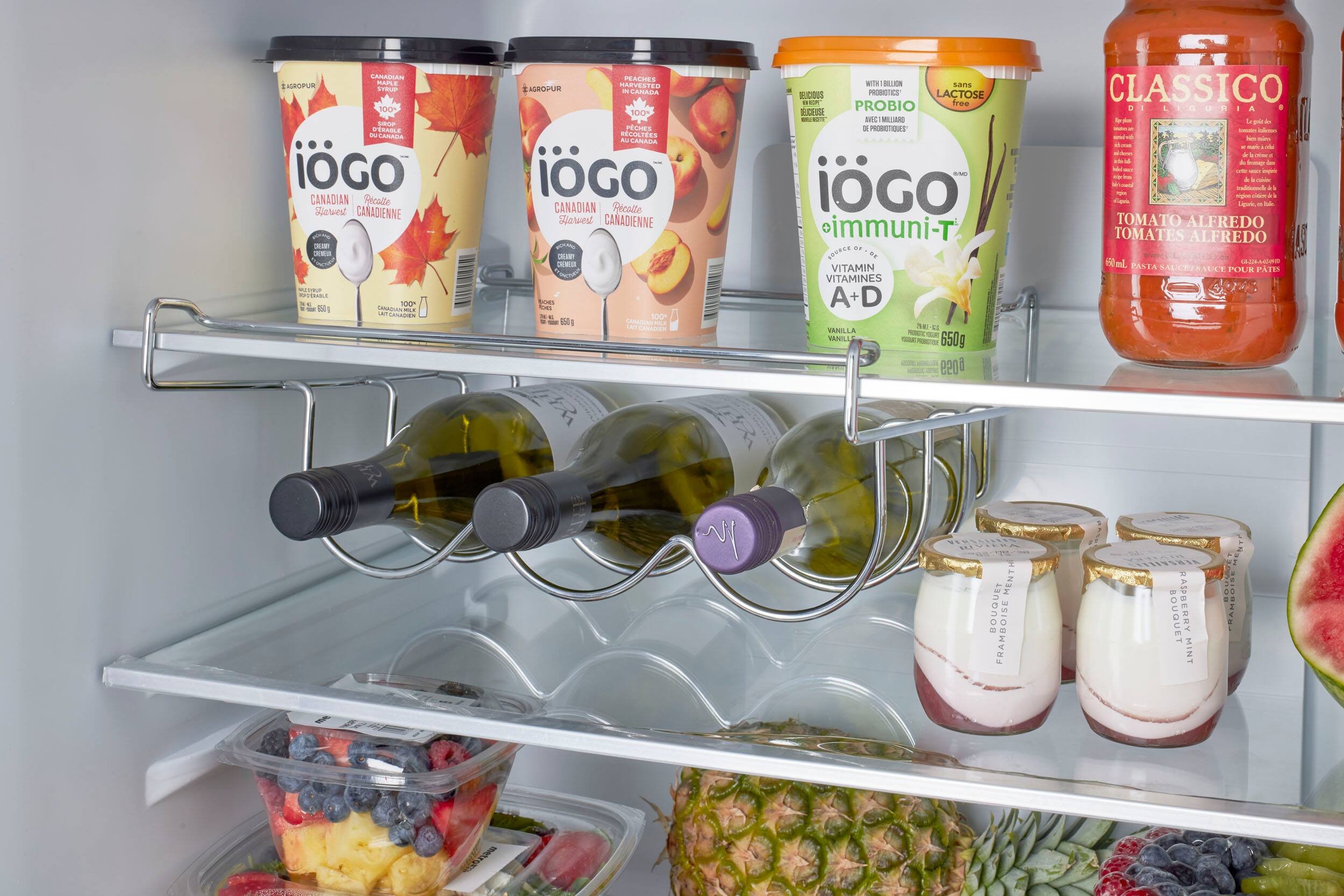 The image shows a refrigerator filled with various food items, including fruits, vegetables, and drinks. There are multiple bottles of drinks, such as milk and juice, placed on different shelves. Some of the fruits include apples, bananas, and oranges. The vegetables consist of broccoli and carrots. The refrigerator is well-stocked with a variety of food items, making it a convenient and healthy option for meal planning.