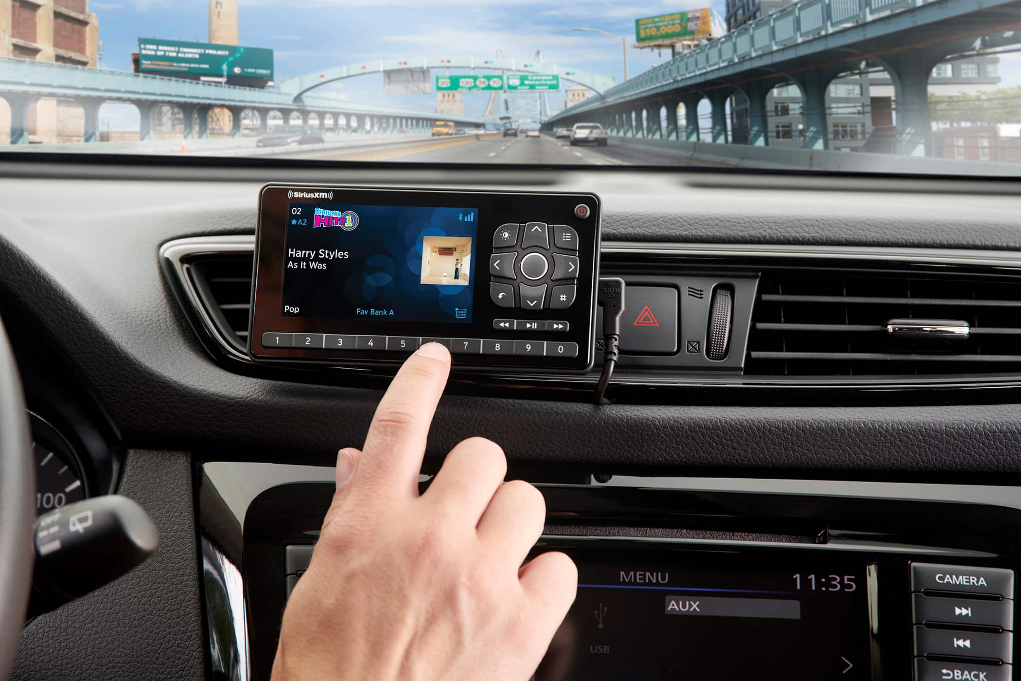 The text on the image reads:
"P $10,000 10 Siriusxm 02 SAION * A2 HITS D ill 11 Harry Styles As It Was xm Pop Fav Bank A II 1 2 3 4 5 7 8 9 0 100 A MENU AUX 11:35 CAMERA N USB > K SBACK"
The text is a mix of various elements, such as a menu, a USB connection, and a camera. It seems to be describing a car's entertainment system or a navigation system. The text also contains a reference to Harry Styles and a SiriusXM radio station.
