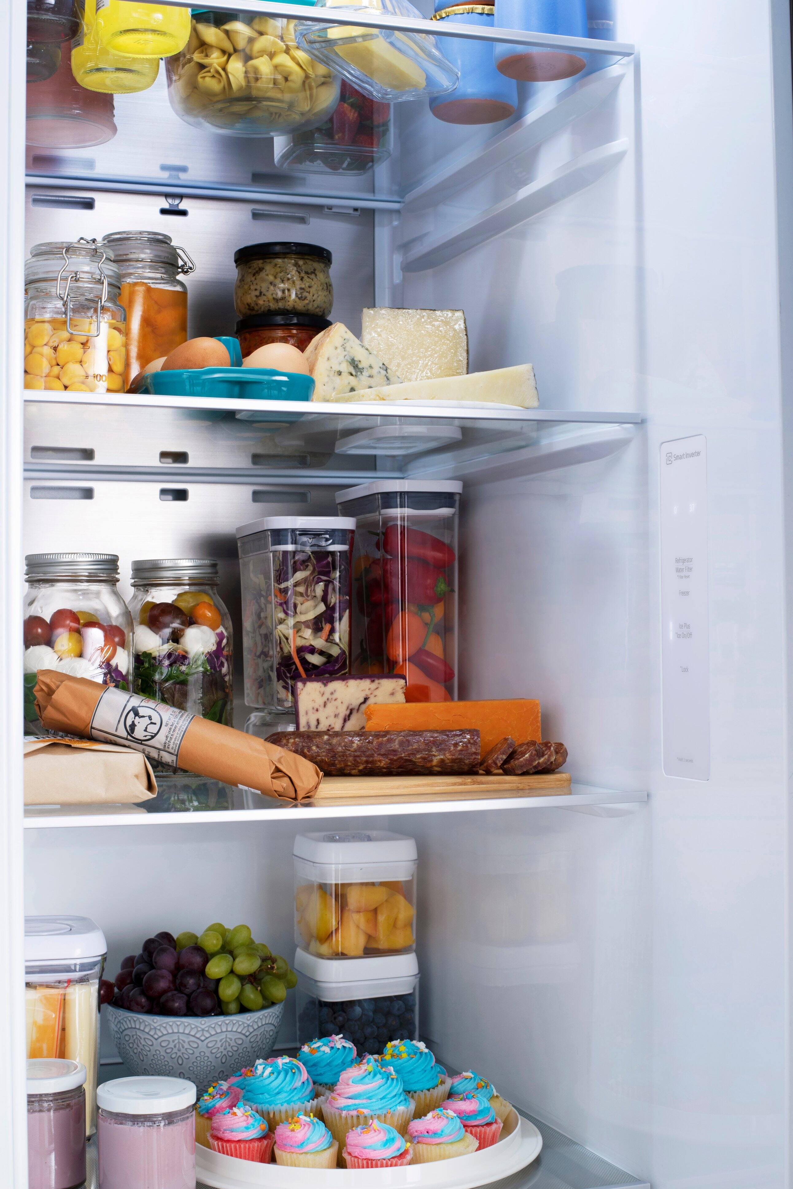 The image shows a refrigerator filled with various food items. There are multiple bottles, including one on the top shelf and another on the middle shelf. The refrigerator also contains a cupcake, which is placed on the bottom shelf. The refrigerator is well-stocked, with a variety of food items and drinks to choose from.