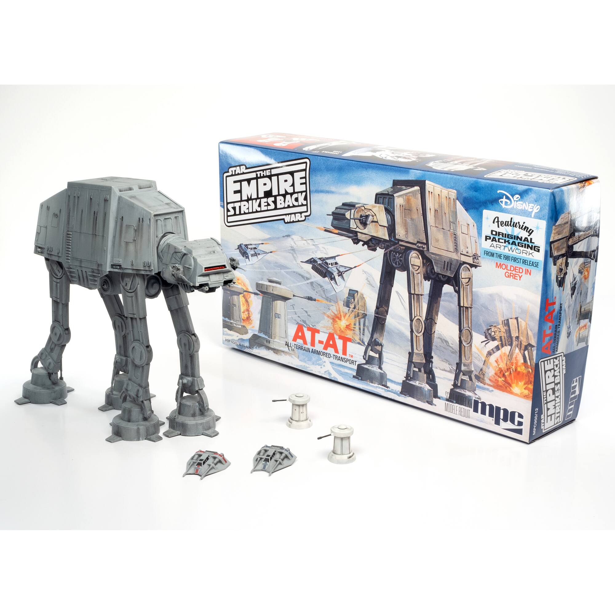 The Empire Strikes Back Star Wars AT-AT toy set is displayed in its original packaging. The set includes a grey AT-AT, a snow speeder, and a tie fighter. The packaging features a Disney logo, indicating that it is an official product. The toy set is made by MPC and is designed to be assembled and played with. The box is white, and the toys are molded in grey.
