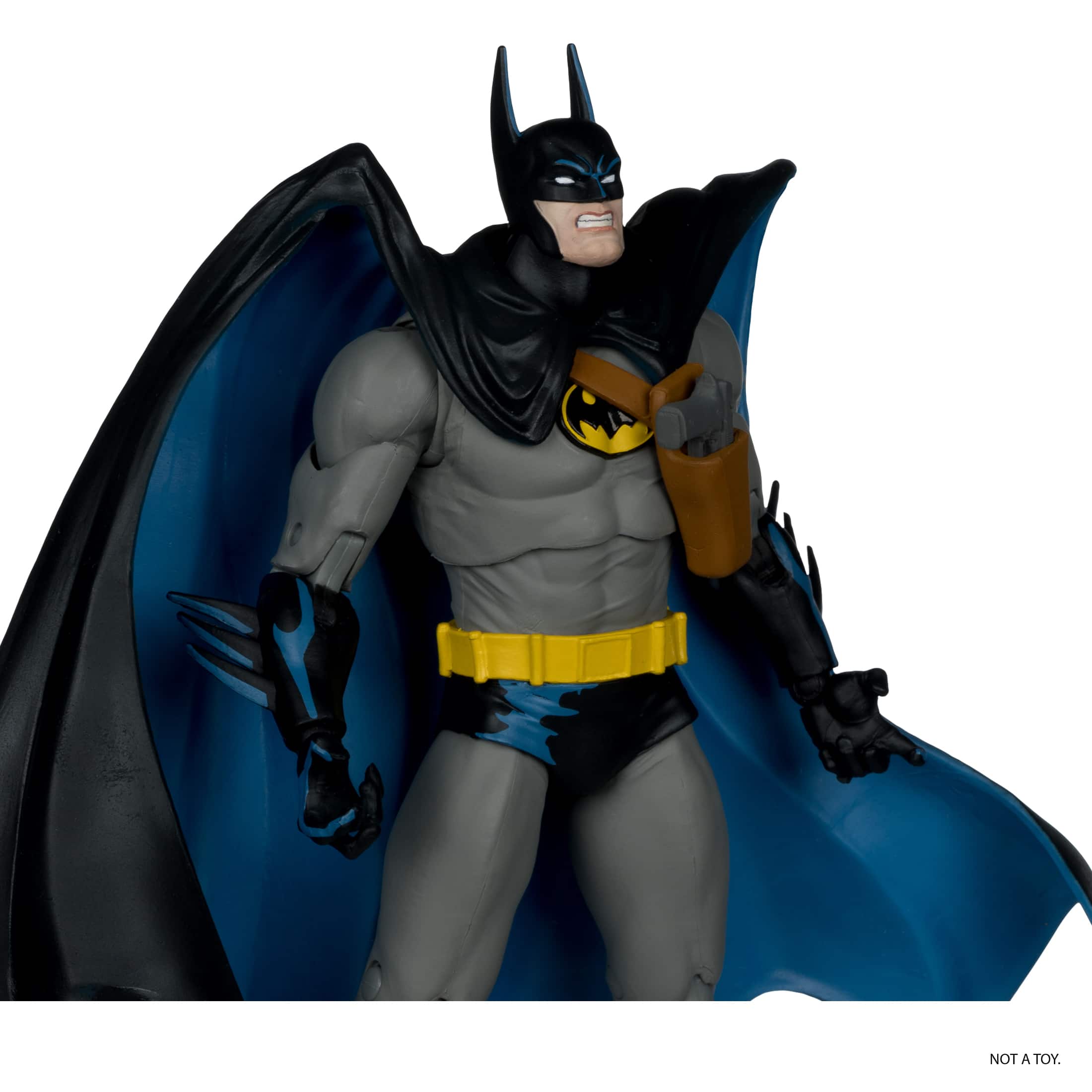 The image shows a Batman action figure, which is a toy. The figure is wearing a cape and is posed with its arms outstretched.