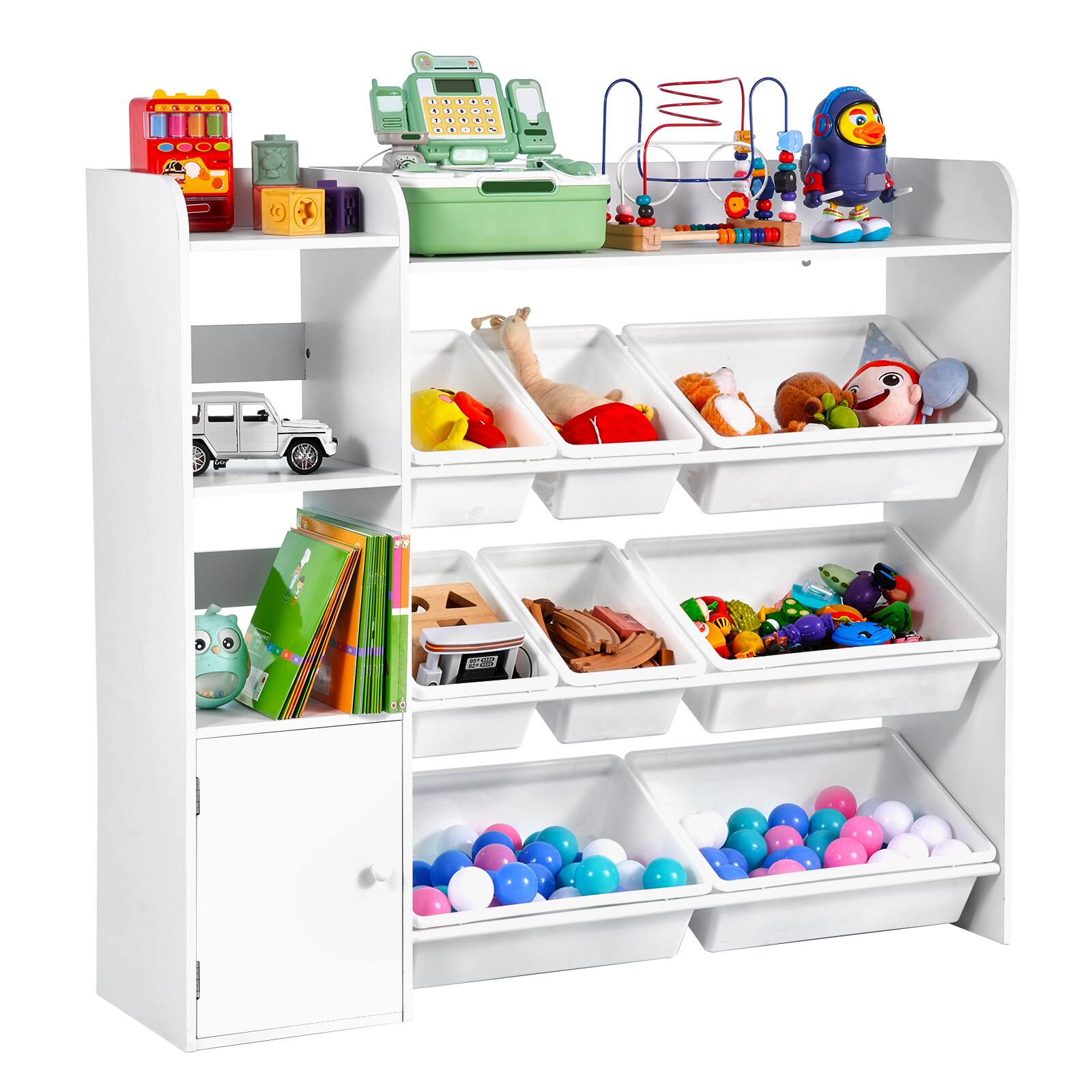 The image shows a white shelving unit filled with various toys and items. On the top shelf, there is a red toy cash register, a green toy cash register, and a blue and white bird-shaped toy. Below that, there are compartments with different toys, including a silver toy car, a yellow and red toy, a brown stuffed animal, and a green and white toy. The middle shelf has a green book with an owl on the cover, a small toy, and a compartment with colorful balls. The bottom shelf has two compartments filled with blue, pink, and white balls.