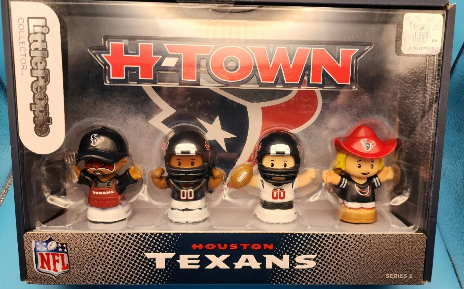 The text on the image is:

"NFL FQV COLLECTOR. HTOWN LA 923879523 LittlePeople I SAR TEXANS 00 0O NFL HOUSTON TEXANS SERIES 1"

Corrected and grouped:

"NFL FQV COLLECTOR. HTOWN LA 923879523 LittlePeople I SAR TEXANS 00 00 NFL HOUSTON TEXANS SERIES 1"