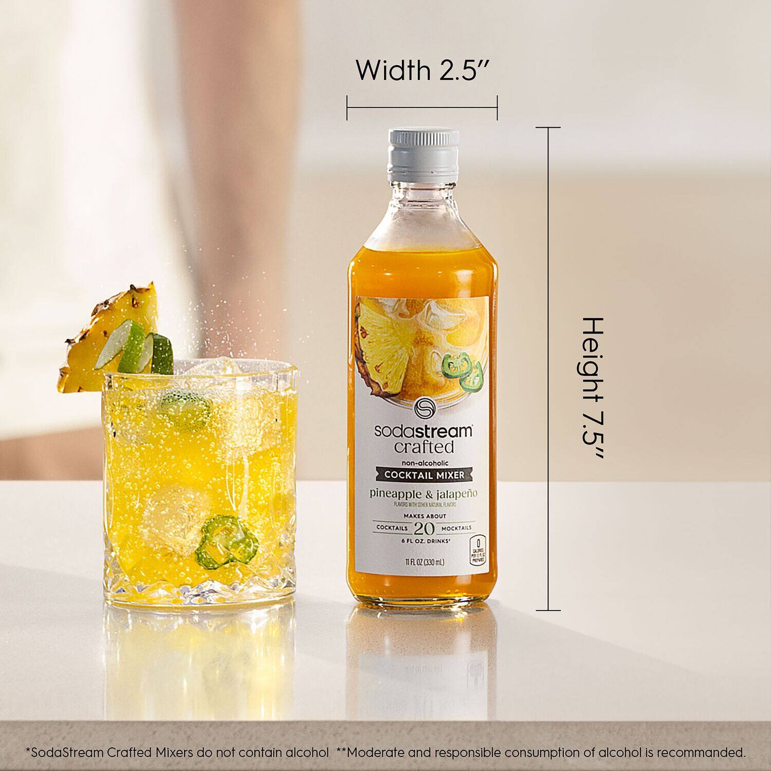 The image shows a bottle of SodaStream crafted non-alcoholic cocktail mixer with pineapple and jalapeno flavors. The bottle is placed next to a glass filled with the mixer, which is ready to be used for making cocktails. The bottle is 2.5 inches wide and 7.5 inches tall, as indicated by the dimensions shown in the image. The SodaStream mixers do not contain alcohol, and moderate and responsible consumption of alcohol is recommended.