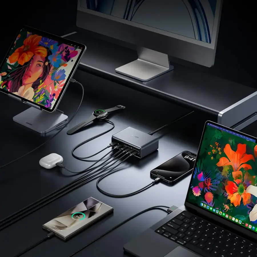 The image features a desk with various electronic devices, including a laptop, a cell phone, and two computer monitors. The laptop is positioned on the right side of the desk, while the cell phone is placed in the middle. The two monitors are located on the left side of the desk. The desk also has a mouse and a keyboard, which are placed near the laptop. The scene suggests a workspace or a home office setup, with the devices ready for use.