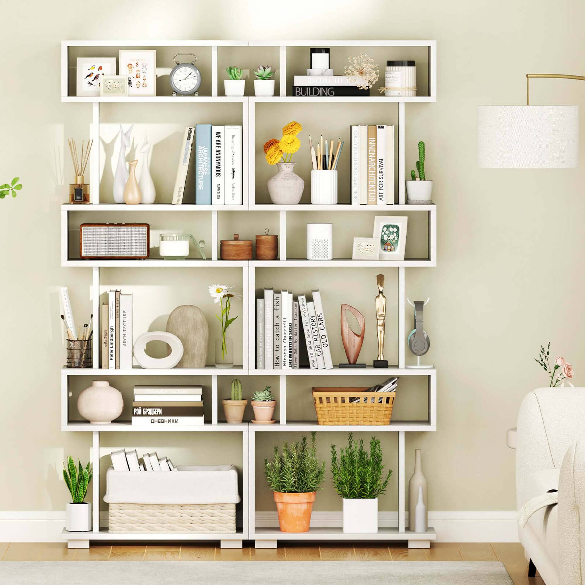 The image features a white bookshelf filled with various items, including books, potted plants, and vases. There are at least five books on the shelf, with some placed towards the top and others towards the bottom. Additionally, there are three potted plants, with one located in the middle of the shelf, another towards the top left, and the third one at the top right. There are also three vases, with one placed in the middle of the shelf, another towards the top left, and the third one at the top right. The bookshelf is situated in a room with a couch nearby, creating a cozy and inviting atmosphere.