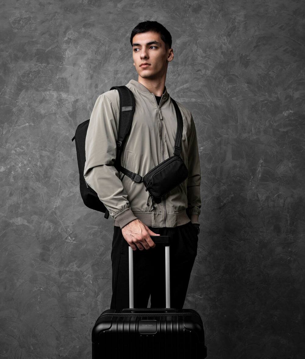 Left. ALPAKA - Bravo Passport Pouch Sling Bag for Men, Passport Holder for Travel, Fits iPhone Pro Max, RFID, AirTag Sleeve - Black Axoflux 210D.