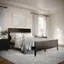 The image shows a bedroom with a large bed positioned under a window. The bed is adorned with a white comforter and a gray throw. The room also features a dresser and a lamp, adding to the cozy atmosphere. The bed is situated on a carpeted floor, providing a comfortable and inviting space for relaxation and rest.