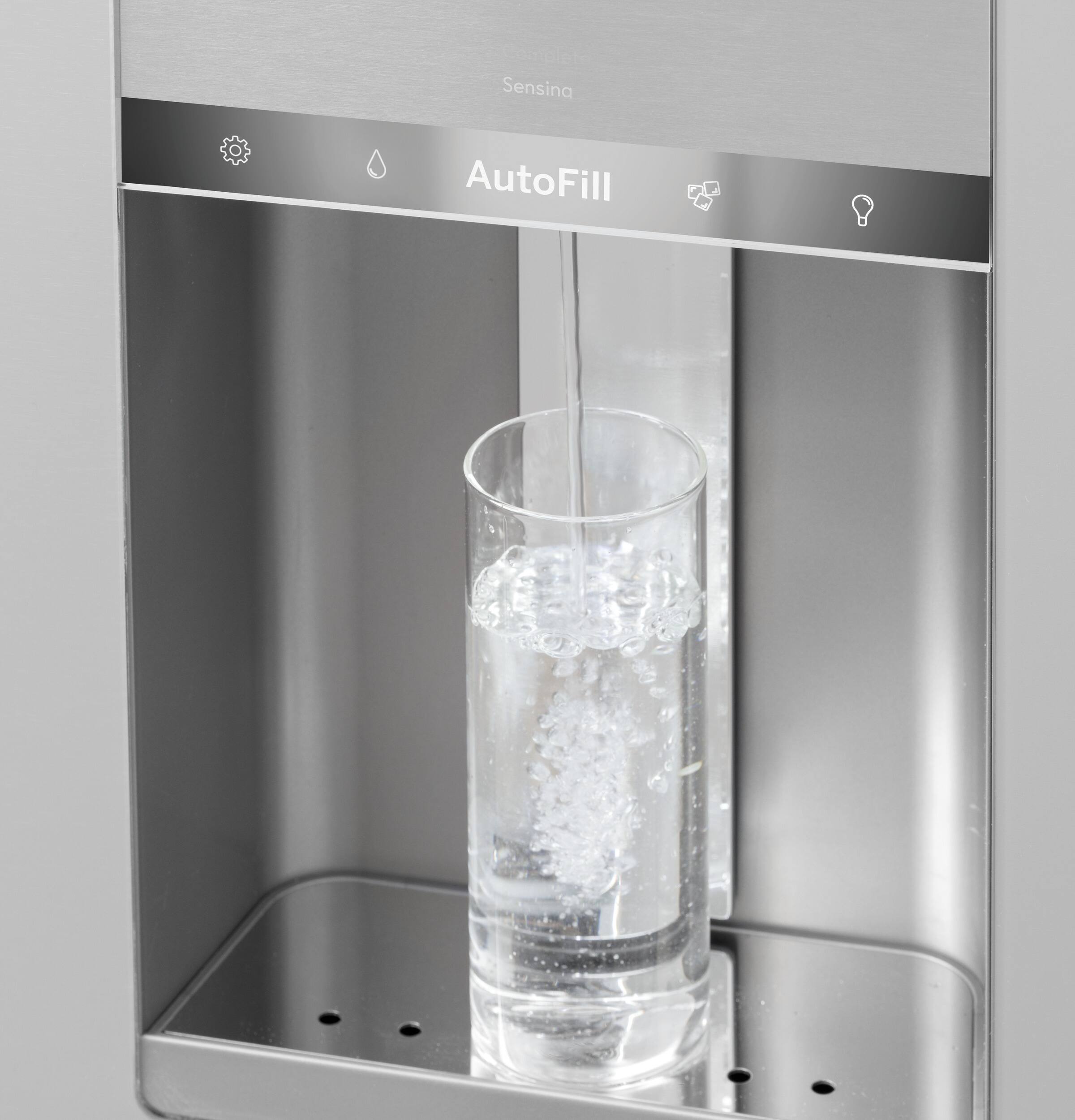 The image features a water dispenser with a glass of water inside. The dispenser is equipped with an auto-fill system, which allows for a continuous supply of water as needed. The water is being dispensed into the glass, and the dispenser is designed to be convenient and efficient for users.