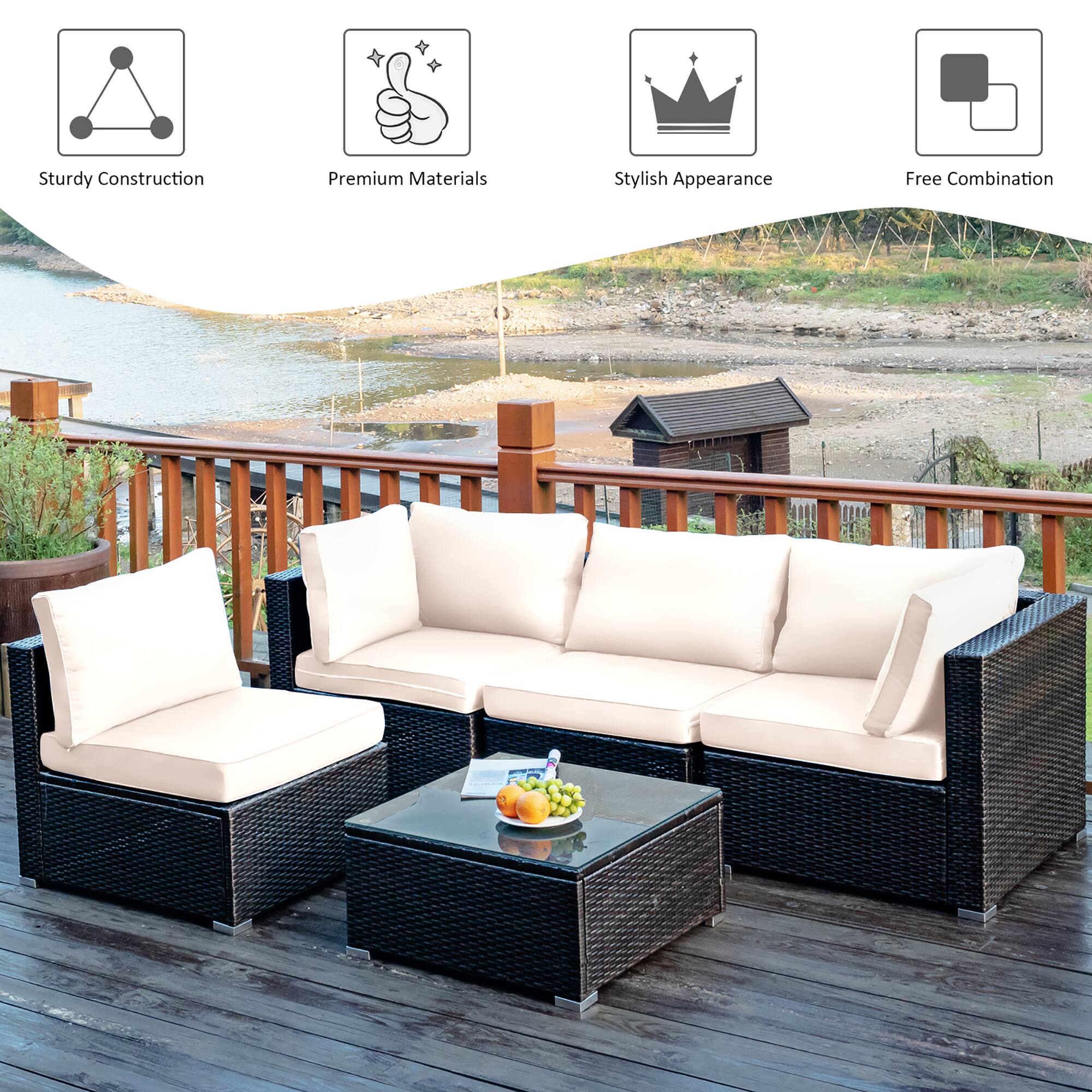 The image features a patio set with a couch, two chairs, and a table. The set is made of wicker and has a stylish appearance. The table is accompanied by a bowl of fruit, including apples and oranges. The patio set is located near a body of water, providing a relaxing and scenic view for those enjoying the space.