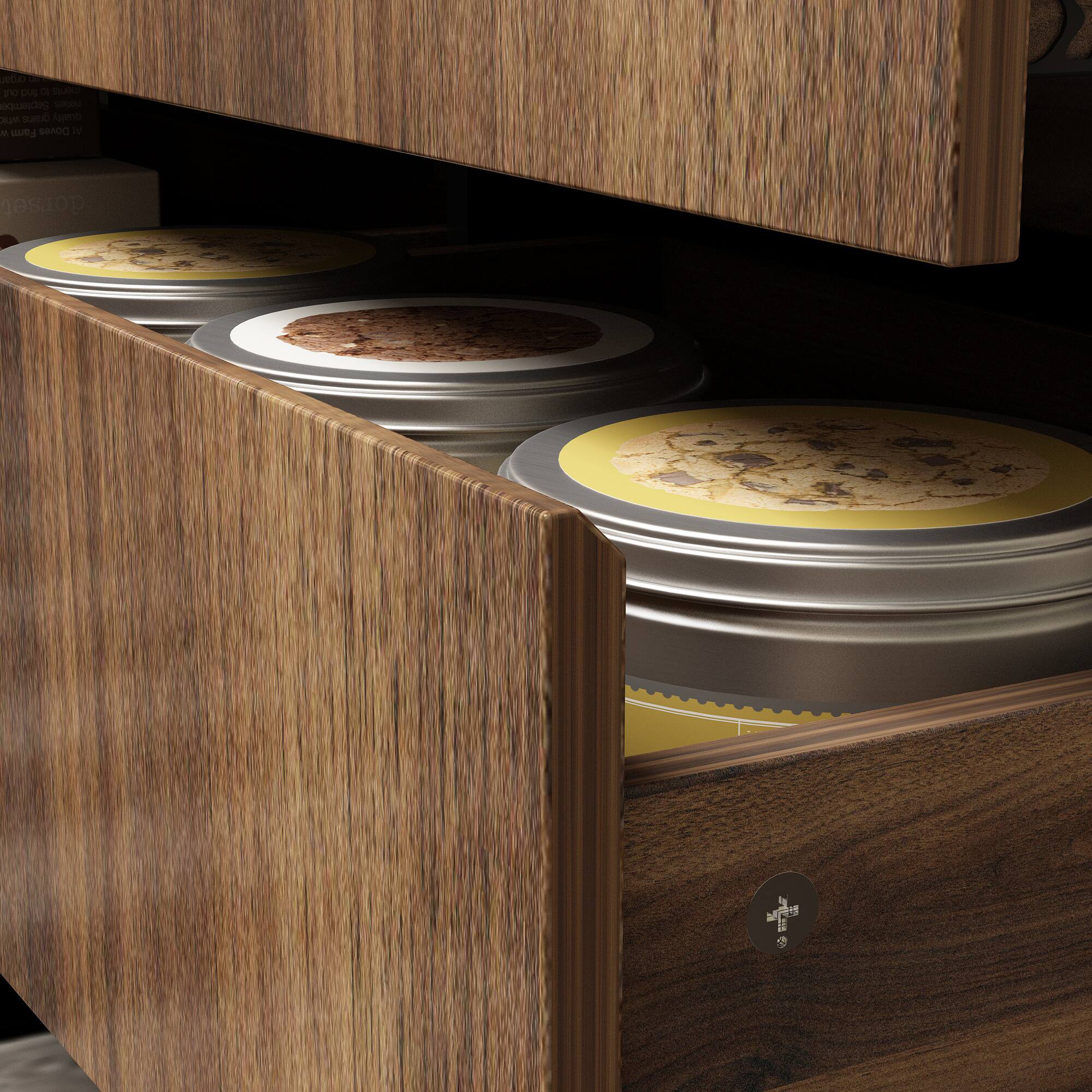 The image shows a wooden drawer with three metal containers inside. The containers are filled with cookies and are placed in a row. The drawer is open, revealing the contents inside. The containers are likely used for storing and organizing the cookies.