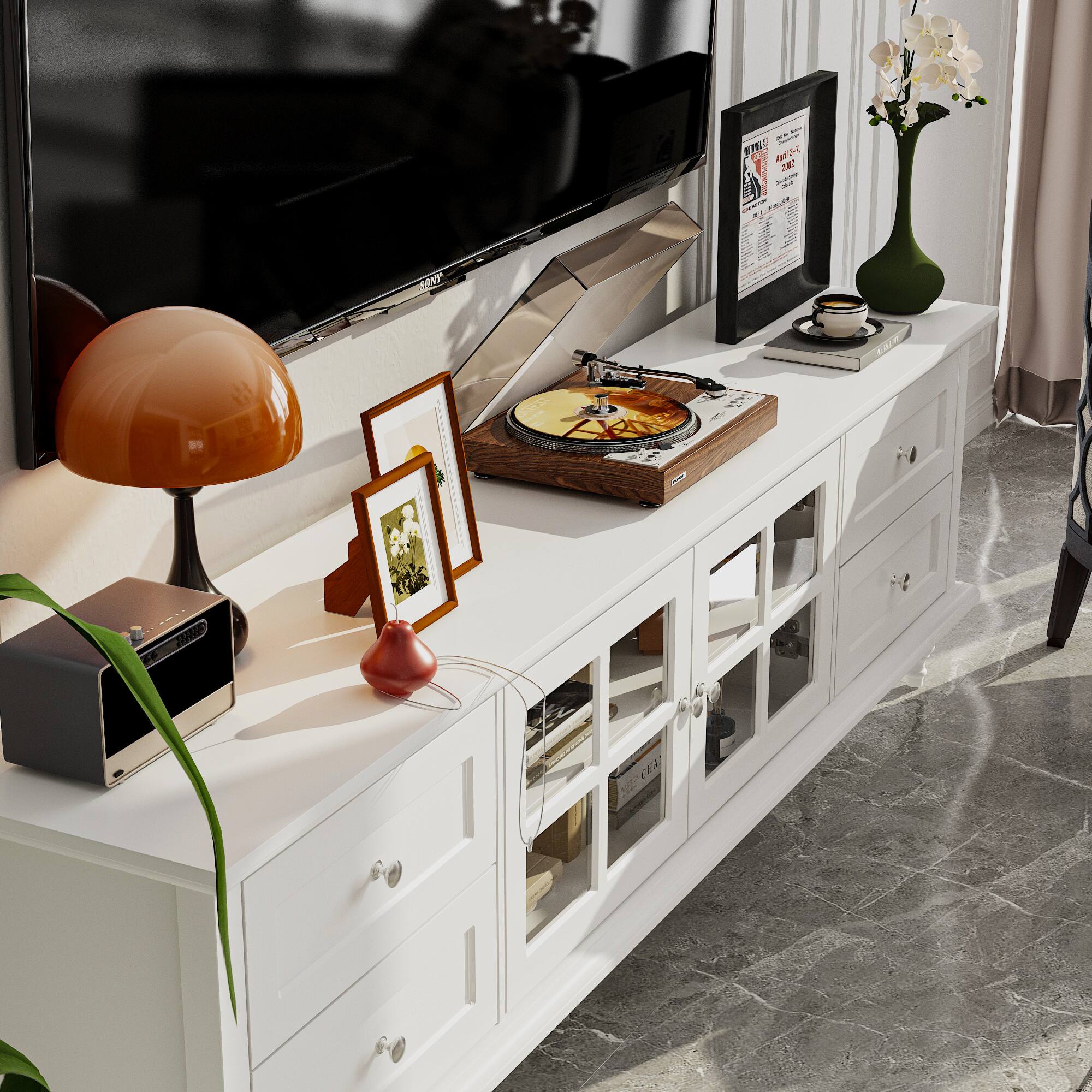 A table with a lamp, a vase, and a record player on it.