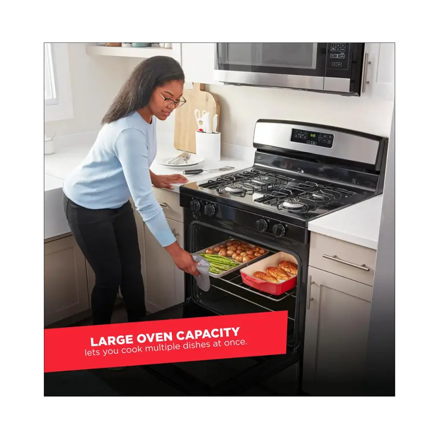 The image features a woman standing in a kitchen, opening the oven door of a large oven. The oven is filled with multiple dishes, indicating its large capacity. The woman is likely preparing to cook or has just finished cooking a meal. The kitchen is equipped with a microwave and a sink, making it a functional space for cooking and cleaning.