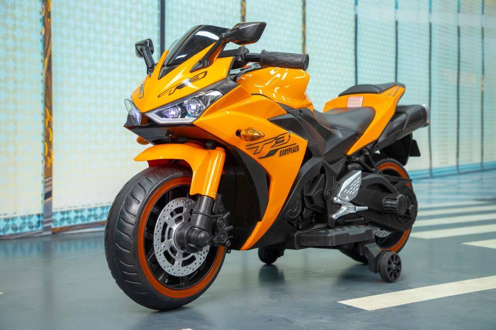 Angle. BreeBe - 12V Kids Electric Motorcycle ride on Toy w/ Training Wheels, Manual Throttle, Lighting Wheels for Ages 3–6 Boys & Girls - Orange.