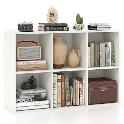 The image features a white bookshelf with various items on it. There are several books of different sizes and colors arranged on the shelves. In addition to the books, there are a few other items on the shelf, such as a vase, a clock, a camera, and a handbag. The arrangement of these items creates a visually appealing and functional display.