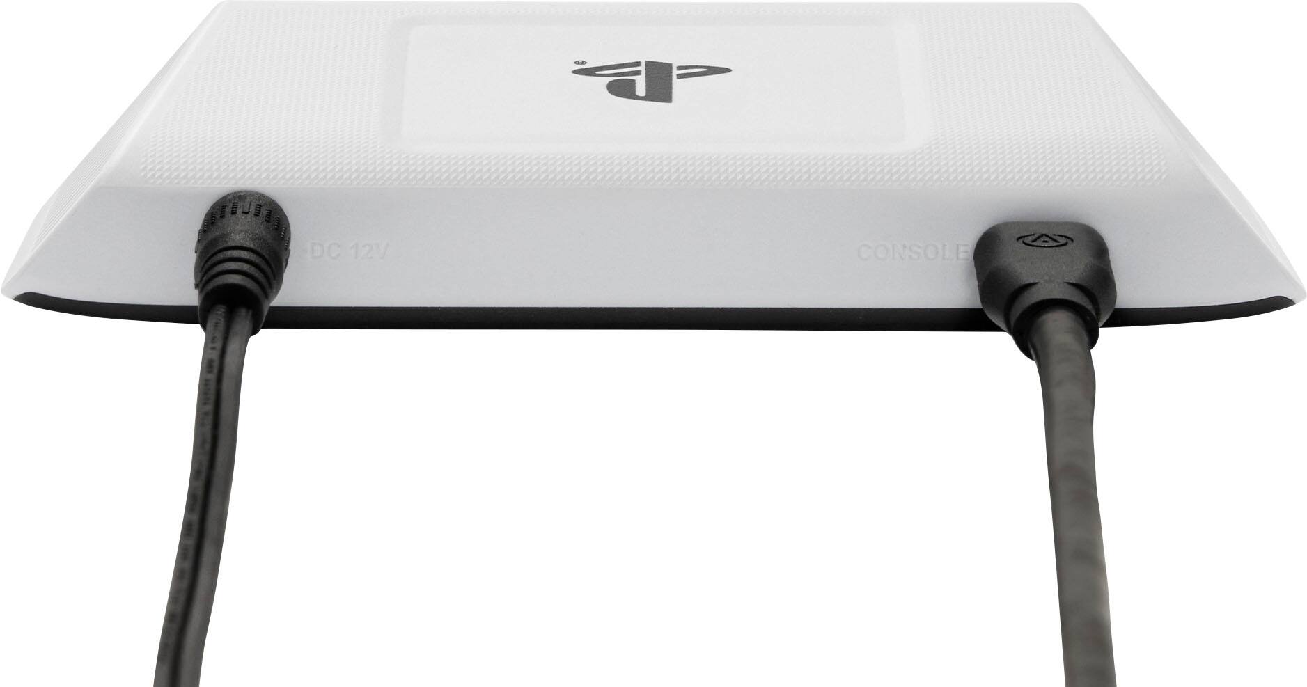 "A white PlayStation 3 console with a black cord plugged into the back."