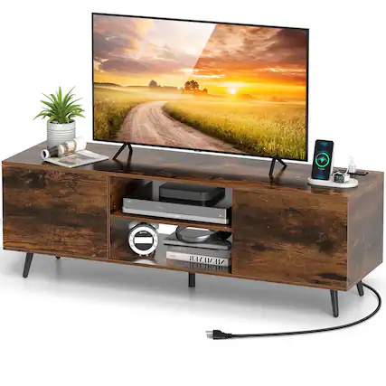 The image features a flat screen TV sitting on top of a wooden stand. The TV is displaying a picture of a road, and there is a potted plant nearby. The TV stand also has a drawer with a remote control and a book inside. Additionally, there is a cell phone placed on the stand.