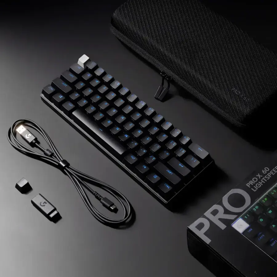 The image features a black keyboard with blue keys, a black case, and a black cord. The keyboard is placed on a black surface, and there is a small box next to it. The keyboard is connected to a computer, and the case is likely used for carrying the keyboard and other accessories. The overall setup suggests a portable and convenient workspace for the user.