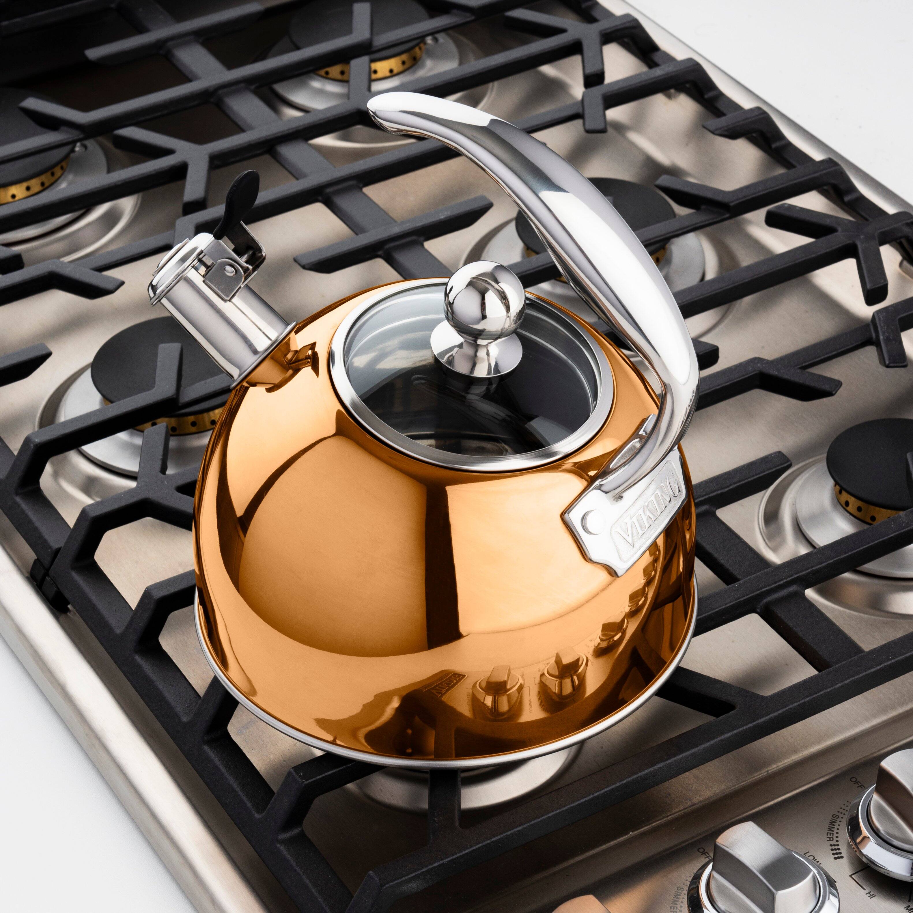 The image features a gold tea kettle sitting on top of a stove. The kettle is positioned on the stove's burner, and it appears to be ready for use. The stove has multiple burners, indicating that it is a functional and versatile cooking appliance. The gold color of the kettle adds a touch of elegance and sophistication to the scene.