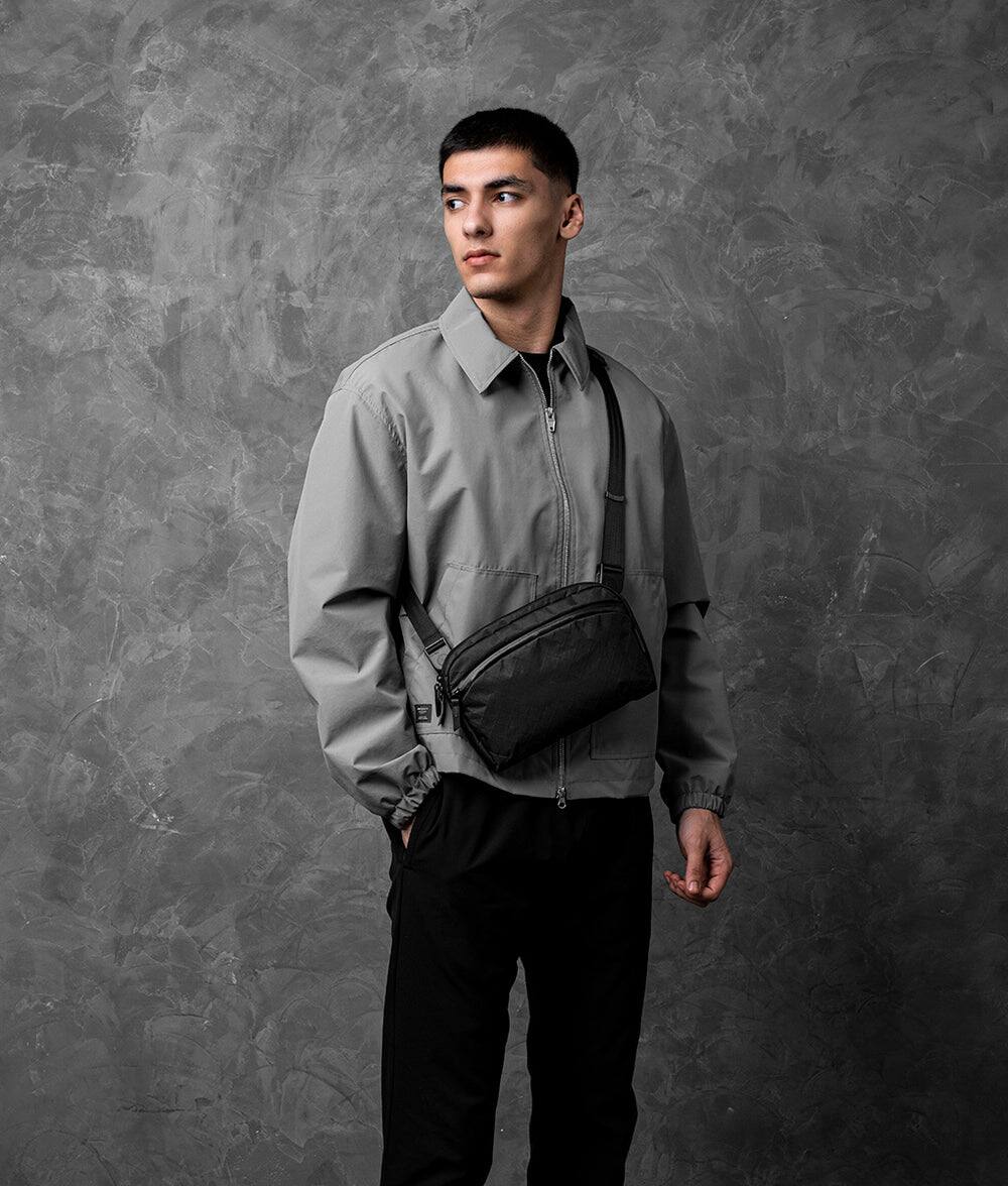 Angle. ALPAKA - Flight Sling 2L Travel Sling Bag, Lightweight Packable Crossbody Pouch, Fits iPad Mini/Switch, Passport Pocket - Black Ultradyne 100D.