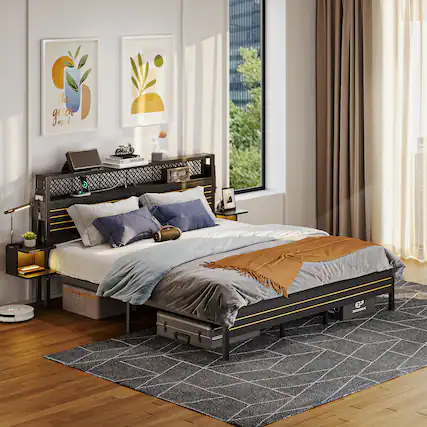 The image features a bedroom with a bed, a nightstand, and a rug. The bed is positioned in the center of the room, with a window nearby. There are two pictures on the wall, one above the bed and another to the left of the bed. The nightstand has a laptop and a cell phone on it, and there is a remote control placed nearby. The room also has a chair and a potted plant, adding to the cozy atmosphere.
