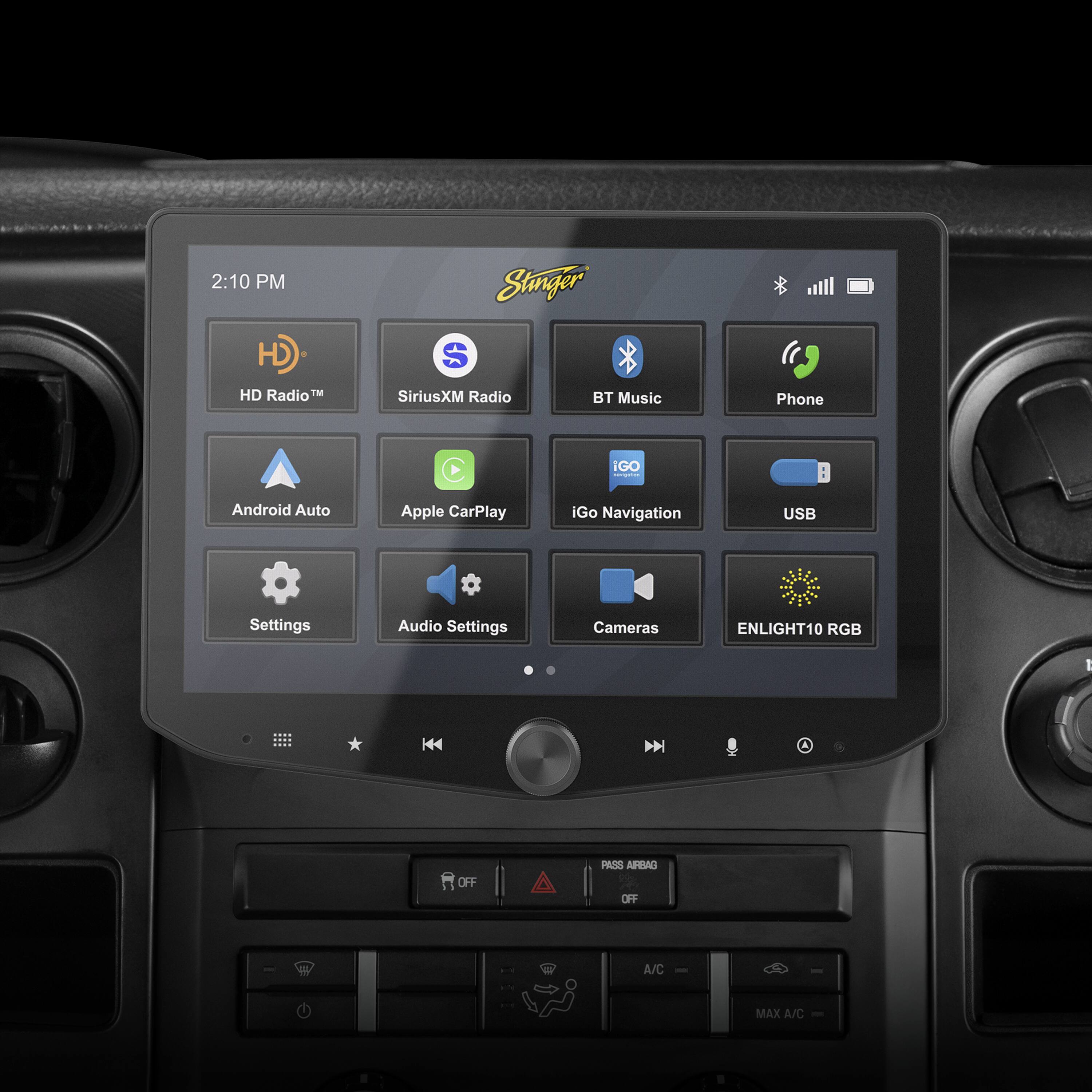 The image shows a car dashboard with a display screen that shows the time as 2:10 PM. The screen also displays various options such as HD Radio, SiriusXM Radio, Bluetooth Music, Apple CarPlay, Android Auto, iGo Navigation, and USB Settings. Additionally, there are options for Audio Settings and Cameras. The car dashboard also has a button for A/C - MAX and A/C.