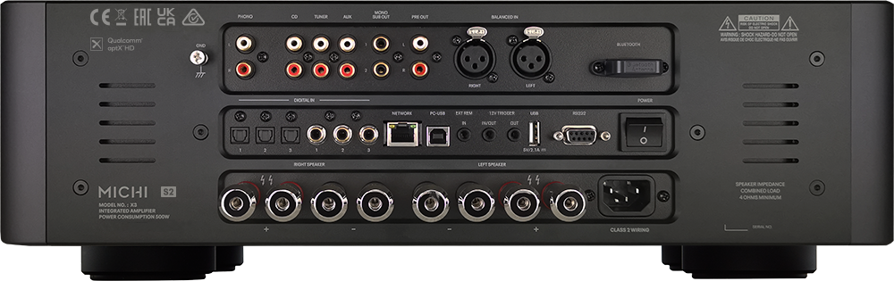 The image shows a black electronic device with a variety of ports and connections. The device has a total of 11 ports, including a USB port, a Bluetooth port, and multiple audio ports. The ports are arranged in a row, with some closer to the front and others towards the back. The device is likely an integrated amplifier, as it is designed to handle multiple audio inputs and outputs. The Michi brand is also visible on the device, indicating its manufacturer.