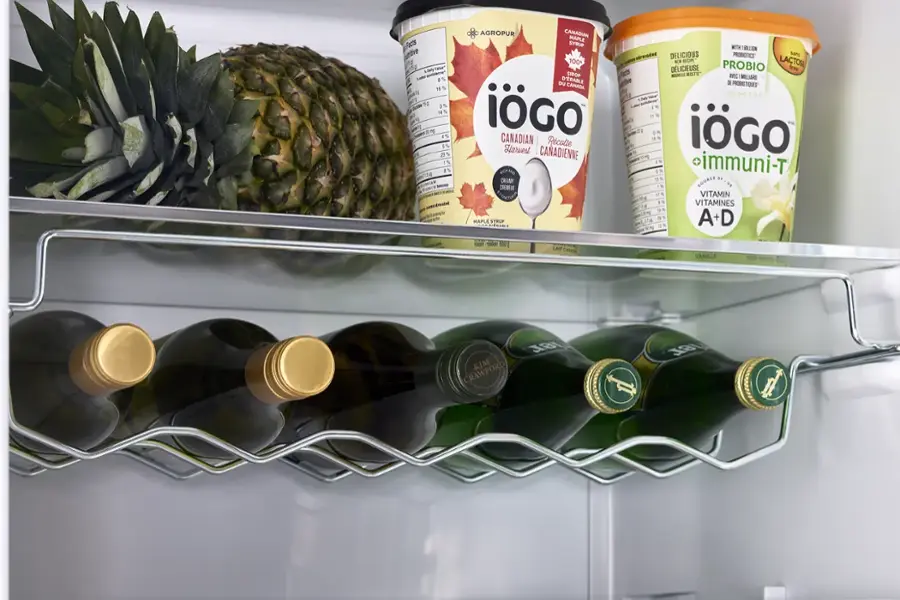 The image features a refrigerator with several items on the shelves. There are two bottles of wine, one on the left side and the other on the right side of the refrigerator. In addition to the wine, there are two yogurt containers, one on the top shelf and the other on the middle shelf. A pineapple is also present in the refrigerator, placed on the top shelf. The refrigerator is filled with a variety of food and drink items, making it a well-stocked and organized space.