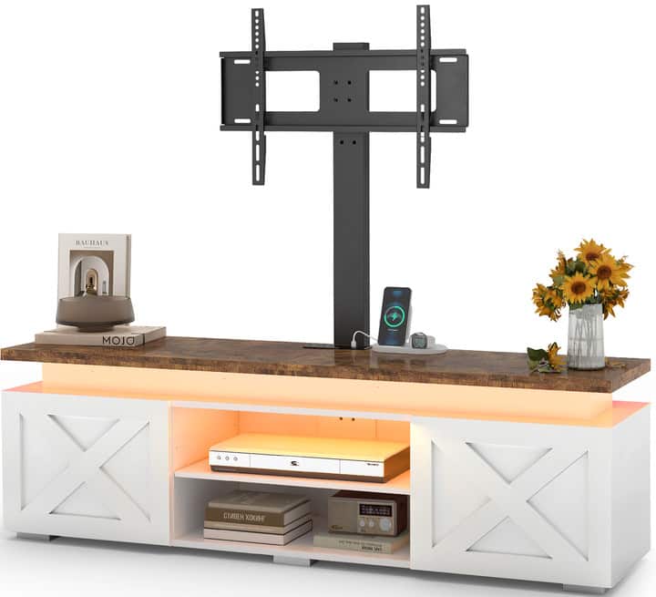 The image features a wooden desk with a TV mounted on the wall above it. The desk has a vase with flowers on it, and there are several books placed on the desk. Additionally, there is a remote control and a cell phone on the desk. The desk is part of a larger entertainment center, which also includes a speaker.