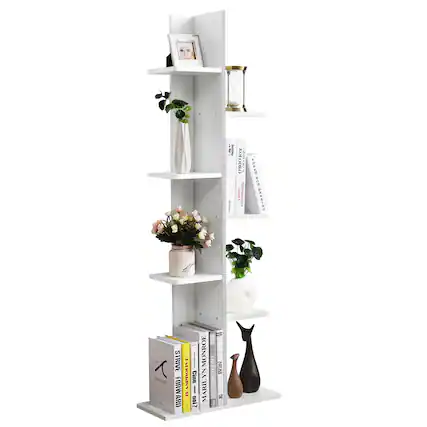 The image features a white bookshelf filled with various items. There are multiple books of different sizes placed on the shelves, as well as several vases of varying sizes and shapes. Additionally, there are two potted plants, one on the left side and the other on the right side of the bookshelf. A cat figurine can also be seen on the right side of the bookshelf. The arrangement of these items creates an organized and visually appealing display.