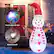 The image features a snowman with a red hat and a scarf, standing in front of a red door. The snowman is holding a light, and there are several other lights in the scene. The image also includes a colorful rotating light and a bright LED light, which are both part of the festive decorations.