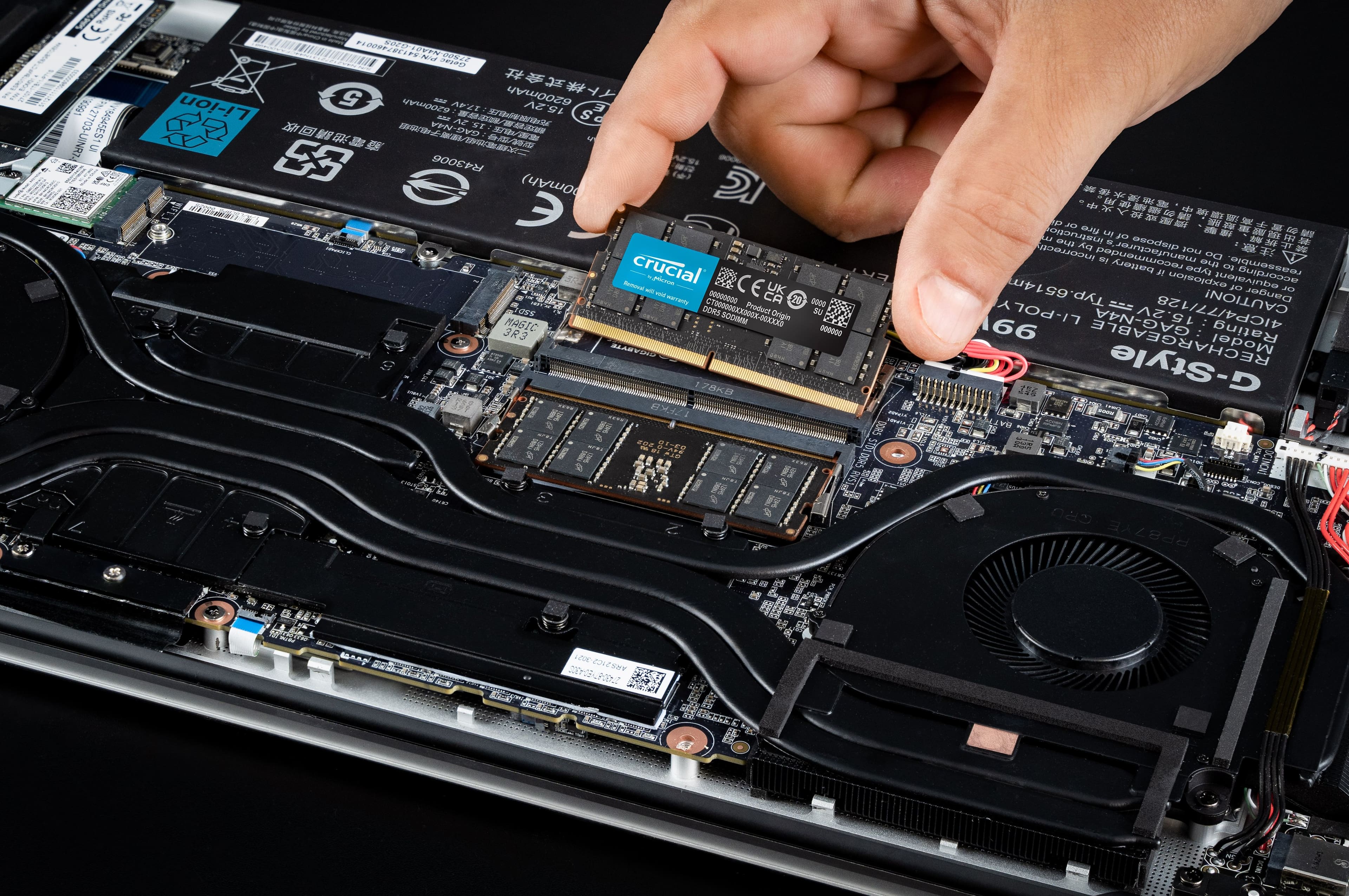 The largest text reads "COR DOR 22 909 Li-ion 5 6200mAh 15.2V F 27703 8494SES1". The image shows a person working on a laptop, specifically removing the battery. The laptop has a 6200mAh battery, and the product origin is the UK.