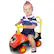 A young boy is sitting in a toy car, which is red and black in color. The toy car has a steering wheel, and the boy is holding onto it while sitting in the driver's seat. The toy car is designed for children to play with and enjoy.