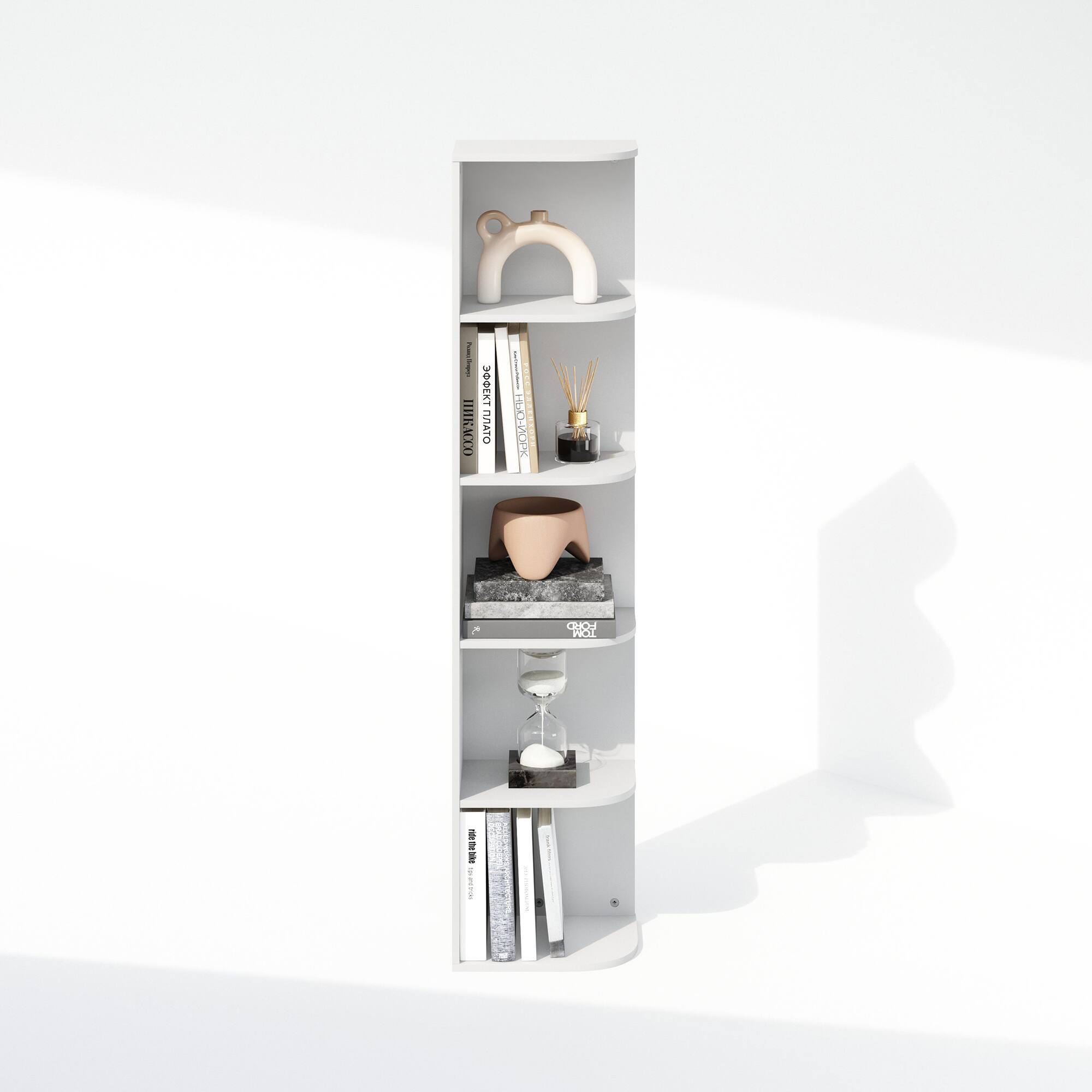 I have a white shelf with several items on it. The top shelf has a white faucet. The second shelf from the top has a few books and a small black and gold diffuser. The third shelf has a beige bowl and a small black tray. The fourth shelf has a white hourglass. The bottom shelf has several books.