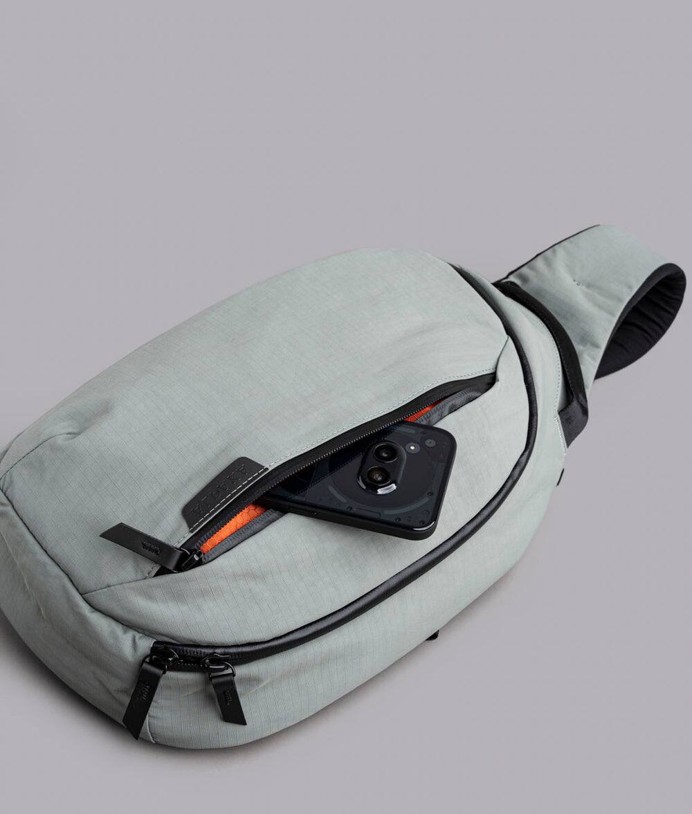Left. ALPAKA - Crossbody Sling Bag 7.5L (Left Shoulder) for Men, Fits 11" Tablet, Phone Sleeve, Bottle Pocket, Luggage Pass-Through - Grey Axoflux 210D.