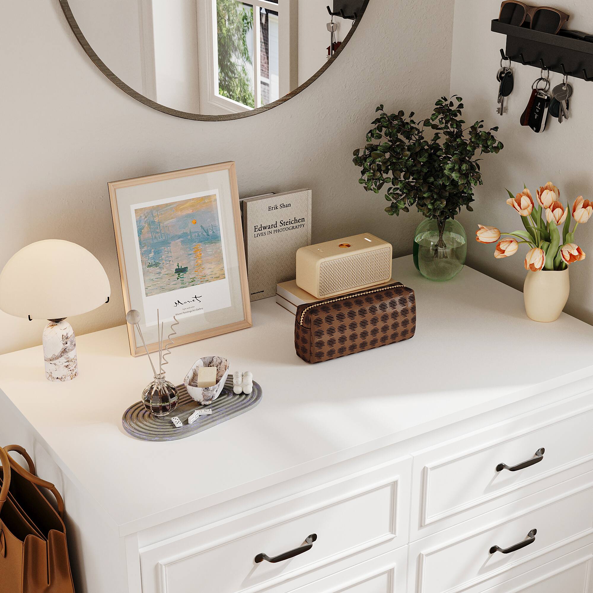 The image features a white dresser with various items on it. There is a mirror above the dresser, and a vase with flowers is placed on the dresser. Additionally, there is a picture frame on the dresser, and a handbag is sitting on the counter. The dresser also has a few books, and a remote control is placed nearby. The overall scene creates a neat and organized appearance.