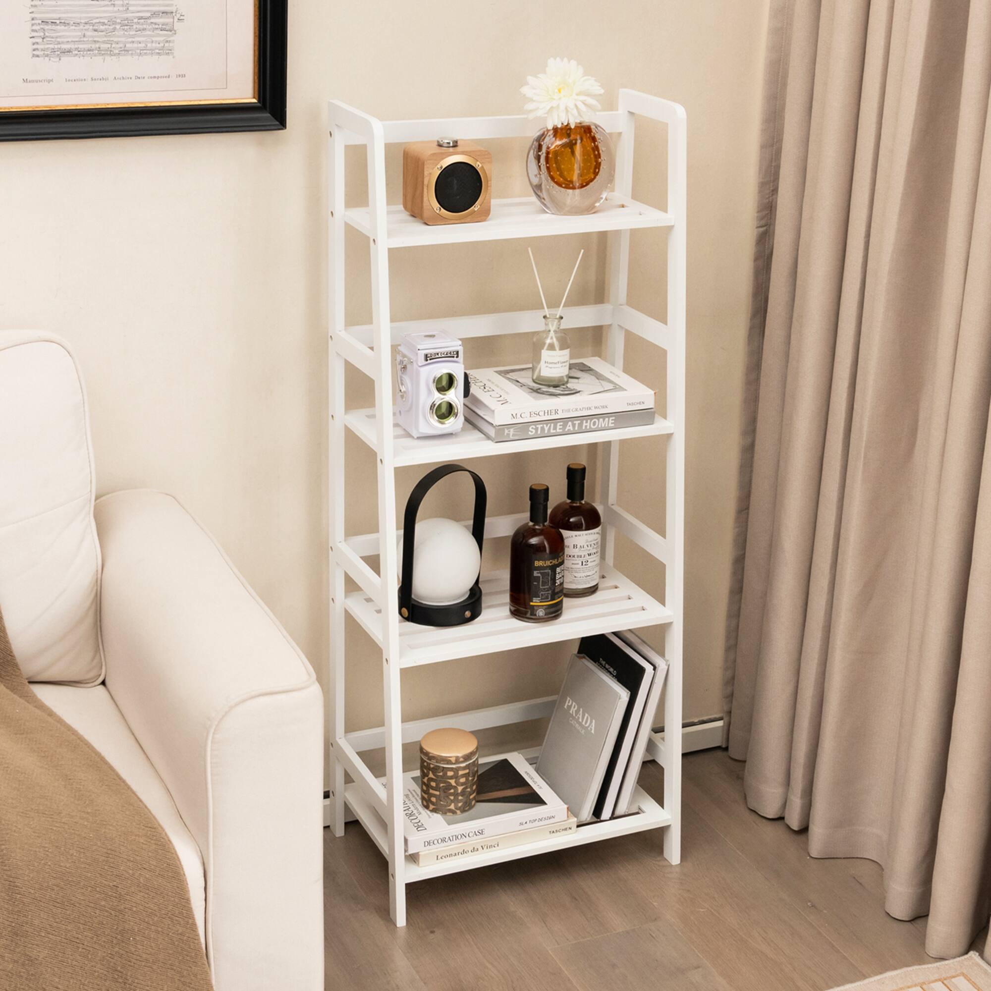 The image features a white shelf with various items on it. There are two bottles, one of which is a Prada perfume bottle. The shelf also has a vase and a book on it. The shelf is placed next to a couch, and there is a picture hanging above the shelf.