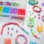 The image shows a variety of craft materials, including beads, yarn, and string, laid out on a table. There are several small beads, some of which are in a container, while others are scattered around the table. The beads come in different colors and sizes, adding to the visual appeal of the craft materials. The table is covered with these materials, creating a vibrant and creative workspace for someone to work on their craft project.
