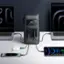 The image features two laptops, a cell phone, and a charger. The charger is connected to the cell phone and the two laptops, which are placed side by side on a table. The cell phone is also connected to the charger, and the charger is plugged into the wall. The scene suggests that the devices are being charged or powered, possibly for use or storage.
