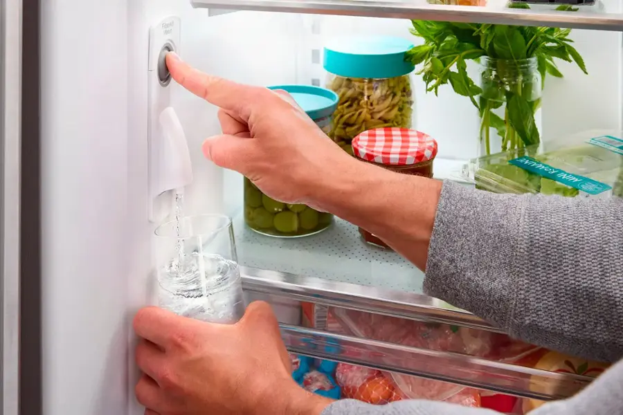 The text on the image reads "Fibre ROMAINE INIY ARD." However, it is not clear what this text is referring to, as it does not seem to be related to the content of the image. The image shows a person opening a refrigerator and pointing to a bottle of water.