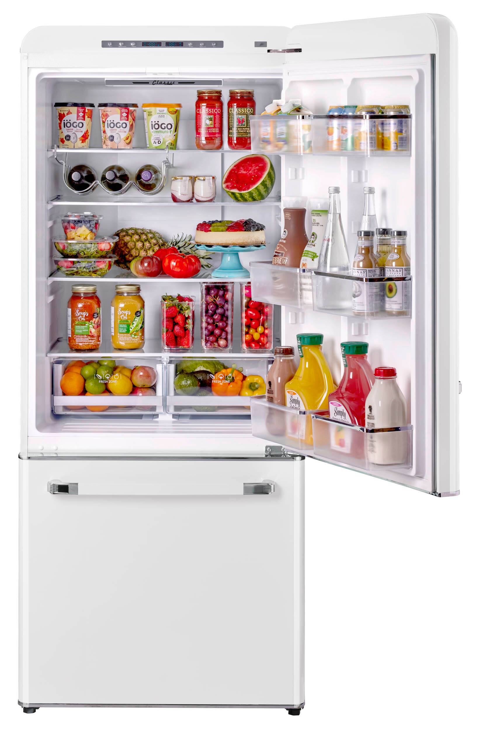The image shows a refrigerator filled with various food items and drinks. There are multiple bottles of juice, milk, and soda, as well as a bowl of fruit. The refrigerator is also stocked with a variety of fruits, including bananas, apples, and oranges. In addition to the food and drinks, there are several jars and bottles placed throughout the refrigerator. The refrigerator is well-organized and filled with a diverse assortment of items, making it an appealing and functional appliance for a home.