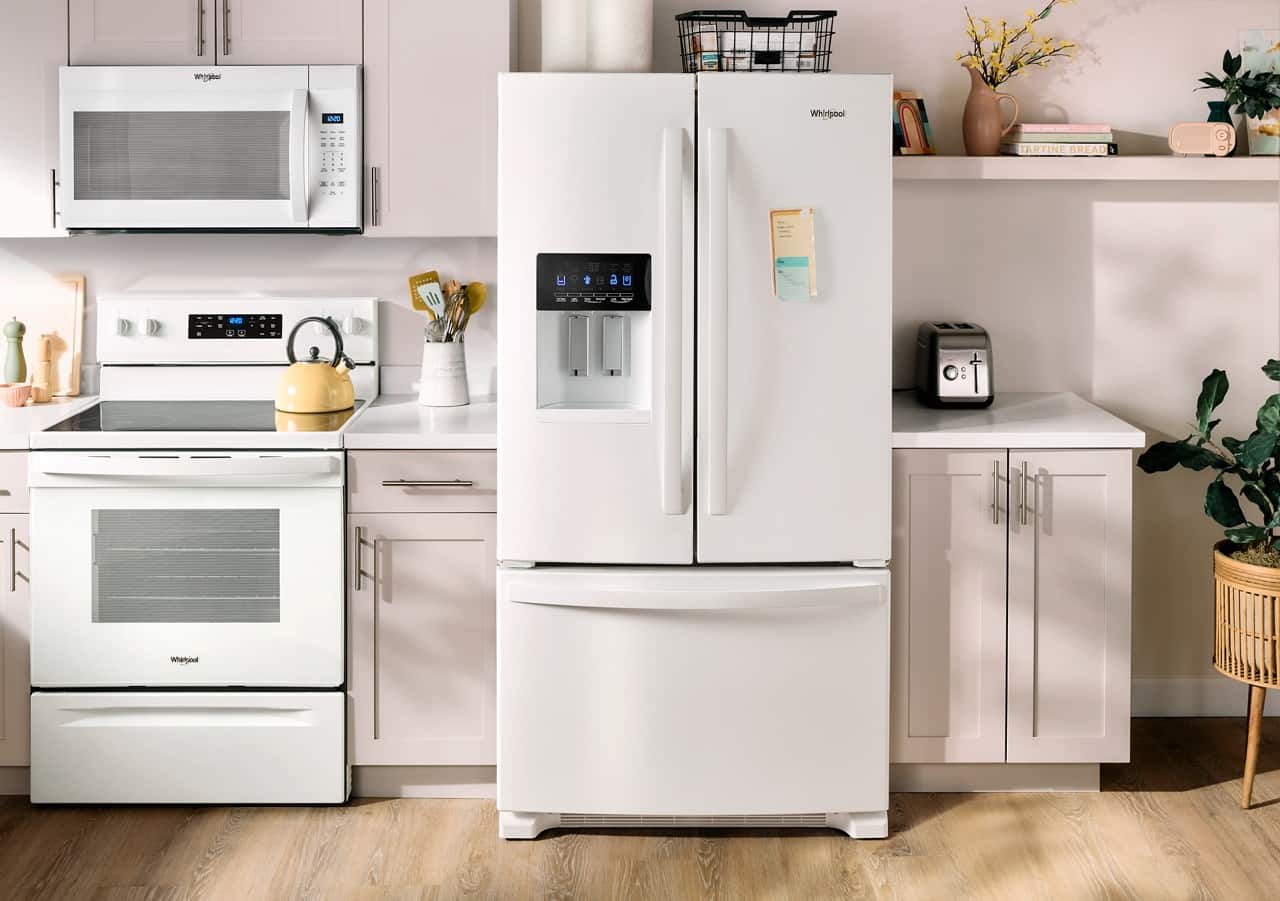 The image features a kitchen with a refrigerator, microwave, oven, and stove. The refrigerator is a large white appliance, and there is a microwave above the oven. The stove is located on the left side of the kitchen. The kitchen also has a sink and a potted plant, adding to the overall ambiance.